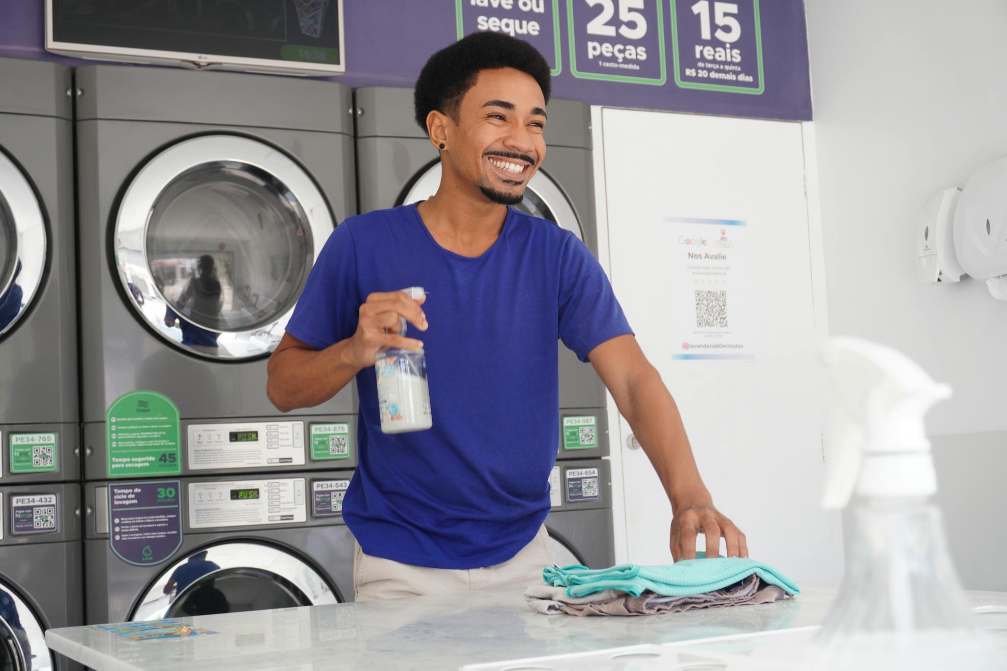 Smiling man folding clothes in a laundromat in Pernambuco, Brazil.